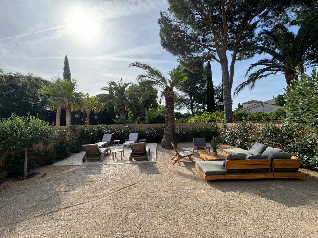 a patio with a couch and chairs and palm trees at Appartement 3ch avec terrasse et jardin à 400m de la plage in Cavalaire-sur-Mer
