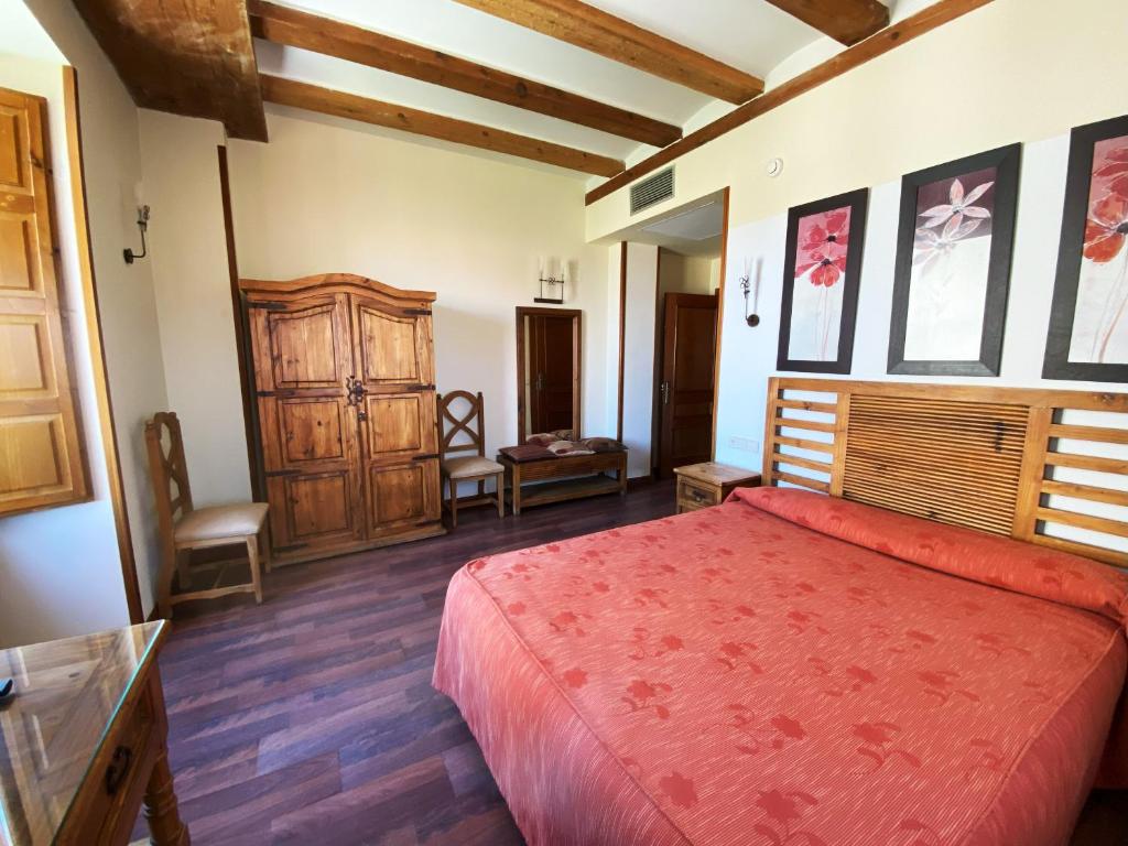 um quarto com uma grande cama vermelha e pisos em madeira em HOTEL EL RASTRO - Palacio Duque de Tamames - em Ávila