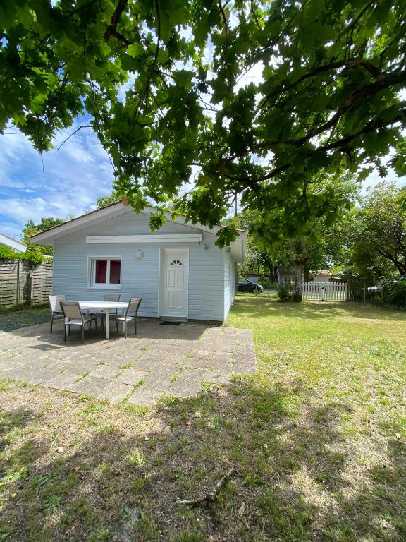 un hangar blanc avec une table et des chaises dans la cour dans l'établissement maison de lachanau, à Hourtin