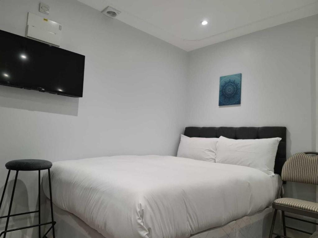 1 dormitorio con 1 cama blanca y TV de pantalla plana en MSK Superior, en Londres