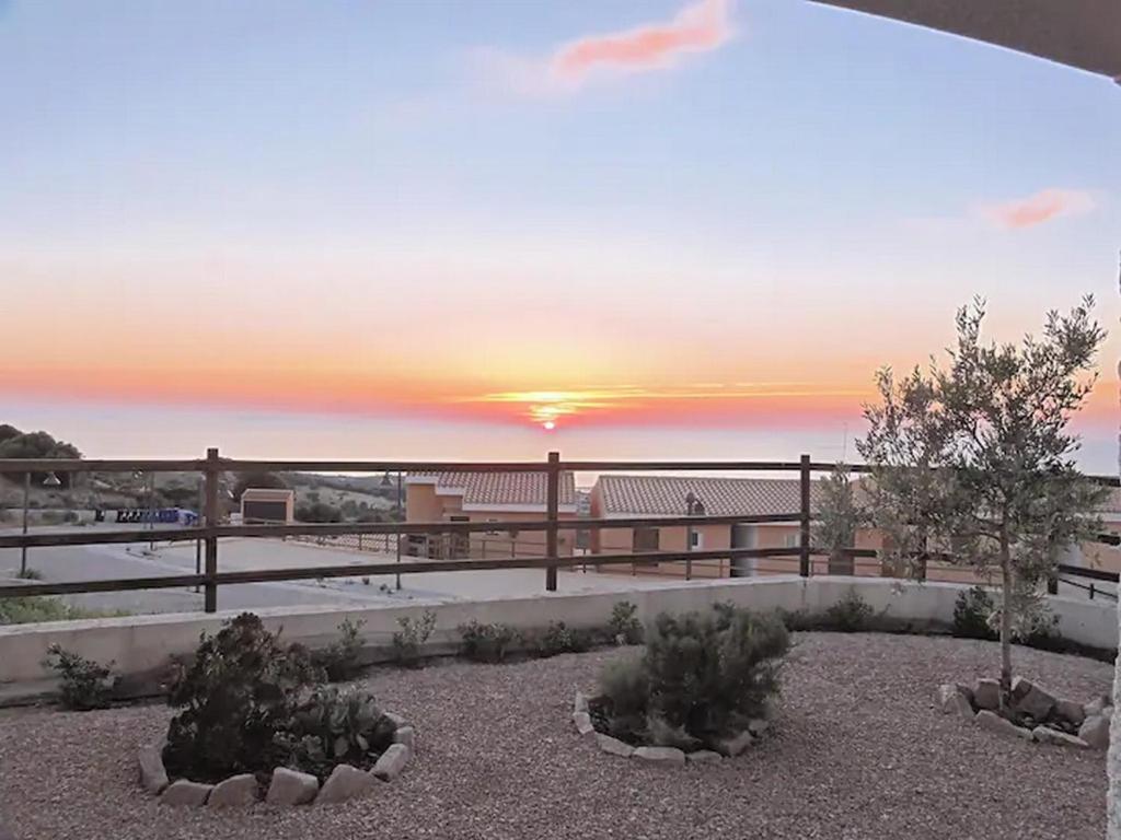 a view of a sunset from a patio with trees at Appartamento il Delfino - Beach House in Isola Rossa