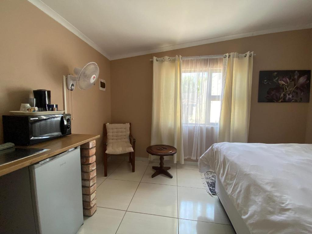 a bedroom with a bed and a desk with a microwave at Inecia's B & B in Uis