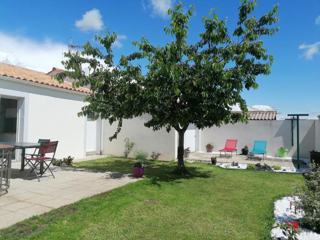 un jardin avec une table, des chaises et un arbre dans l'établissement La Maison des Roses, à Longeville-sur-Mer