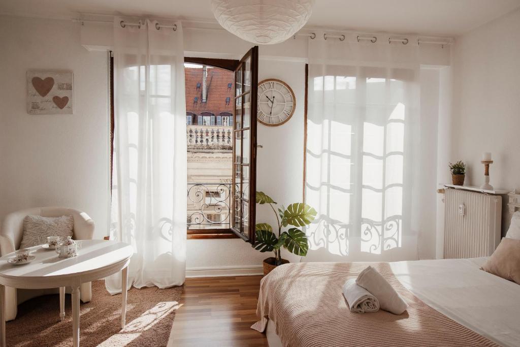 a bedroom with a bed and a table and a clock at Studio cocoon hypercentre Carré d'or de Strasbourg in Strasbourg