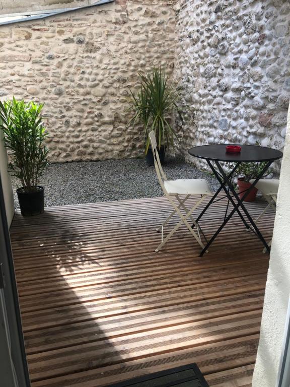 un patio con tavolo, sedie e muro di mattoni di Studio centre ville et terrasse a Romans-sur-Isère