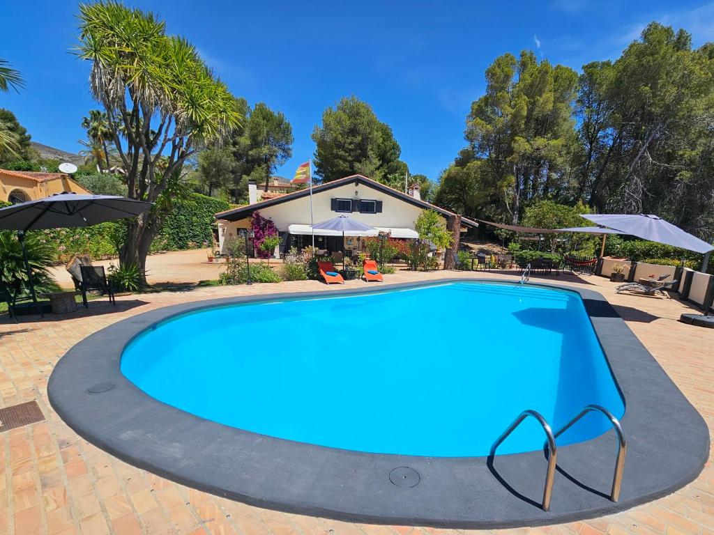 une grande piscine bleue en face d'une maison dans l'établissement Finca la Yuca, à Ontinyent