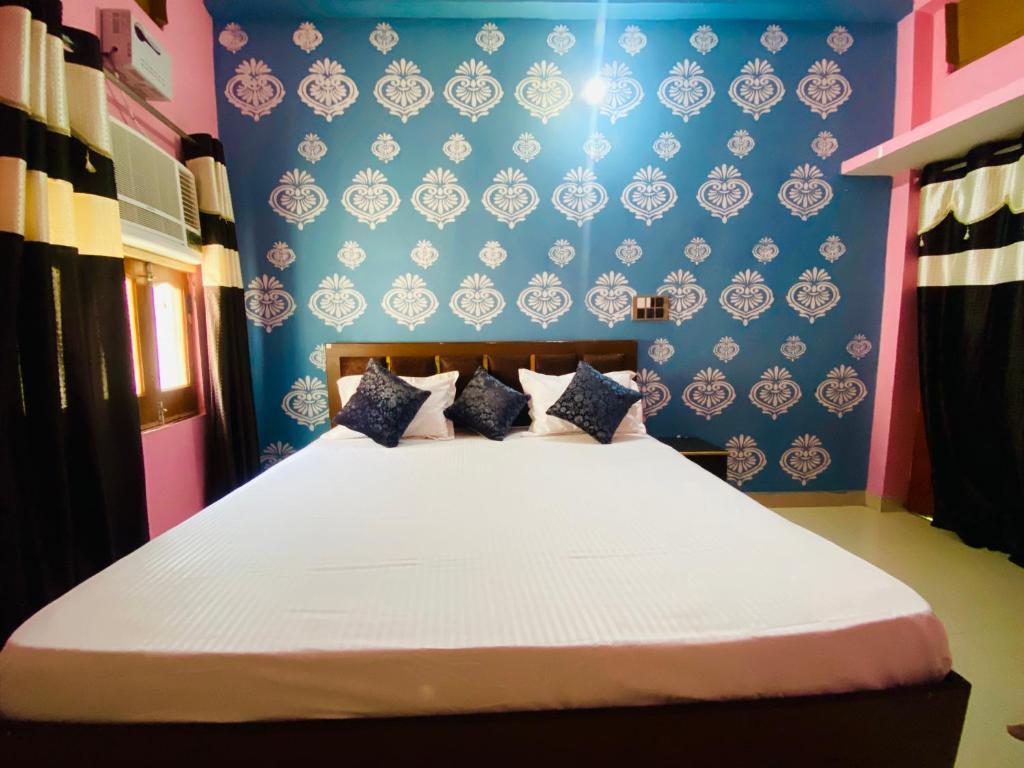 a bedroom with a large bed with a blue wall at The Narayan Bhawan , ramanuj ashram ,haridas nagar ,ramkot ayodhya ji in Ayodhya