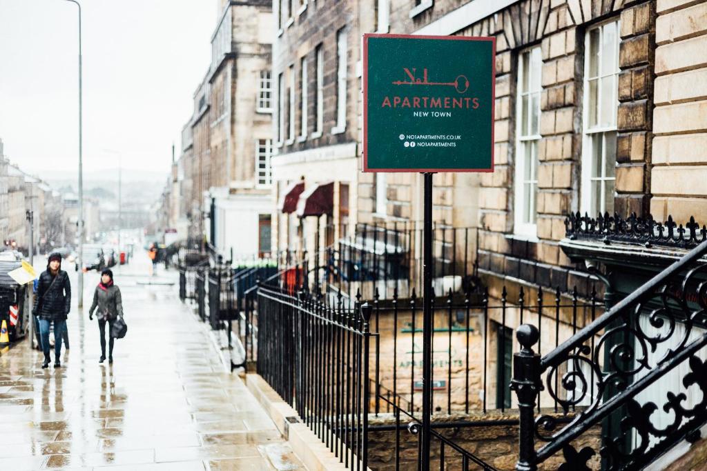 a sign on a street with people walking down the street at No1 Apartments Edinburgh - New Town in Edinburgh