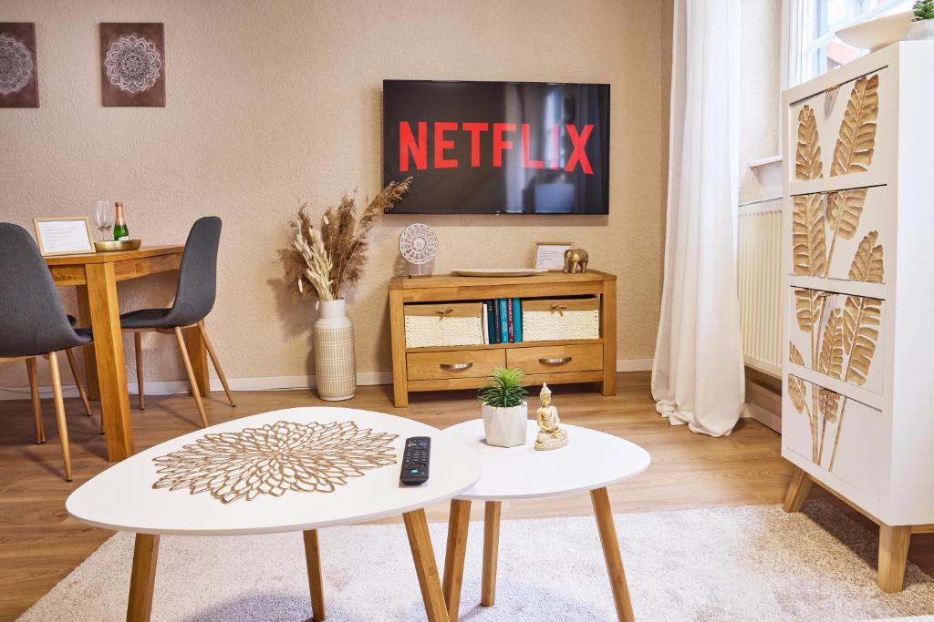a living room with two tables and a tv at IDEE Living: City Apartment am Marktplatz in Heppenheim an der Bergstrasse