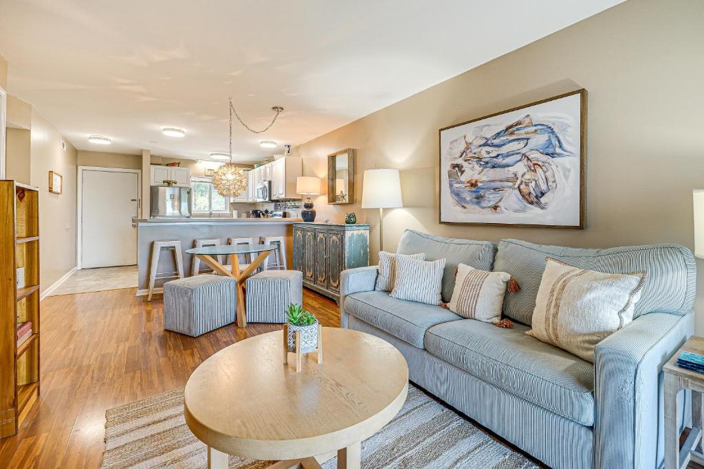 Una sala de estar con un sofá azul y una mesa. en Breezy Carolina Beach Condo with Balcony and Pools!, en Carolina Beach