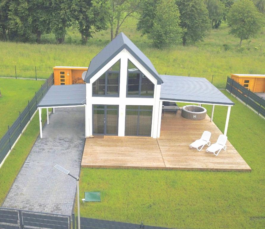 une vue aérienne d'un pavillon avec deux chaises blanches dans l'établissement Ferienhaus Sophia 70qm bis 5 Gäste mit Fass-Sauna, Whirlpool April bis Oktober, 75qm Terrasse und eingezäunten Garten, à Sierosław