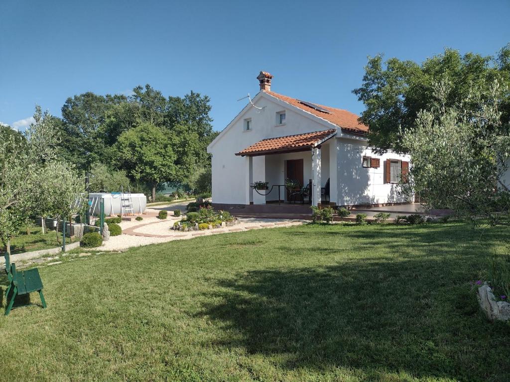 uma pequena casa branca com um jardim de relva em Spignoviza em Kanfanar