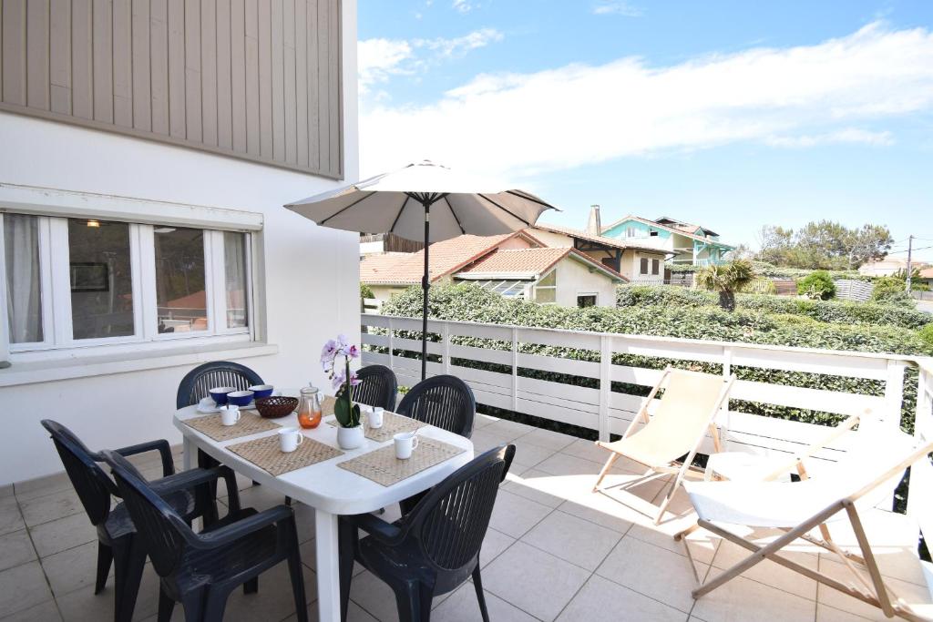 un patio avec une table, des chaises et un parasol dans l'établissement Ben et sou - Hossegor appartement avec agréable terrasse au premier étage d'une villa, à Soorts-Hossegor