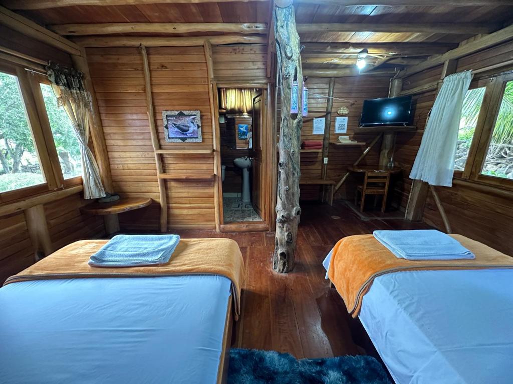 a bedroom with two beds in a wooden cabin at El Pajas in Puerto Velasco Ibarra