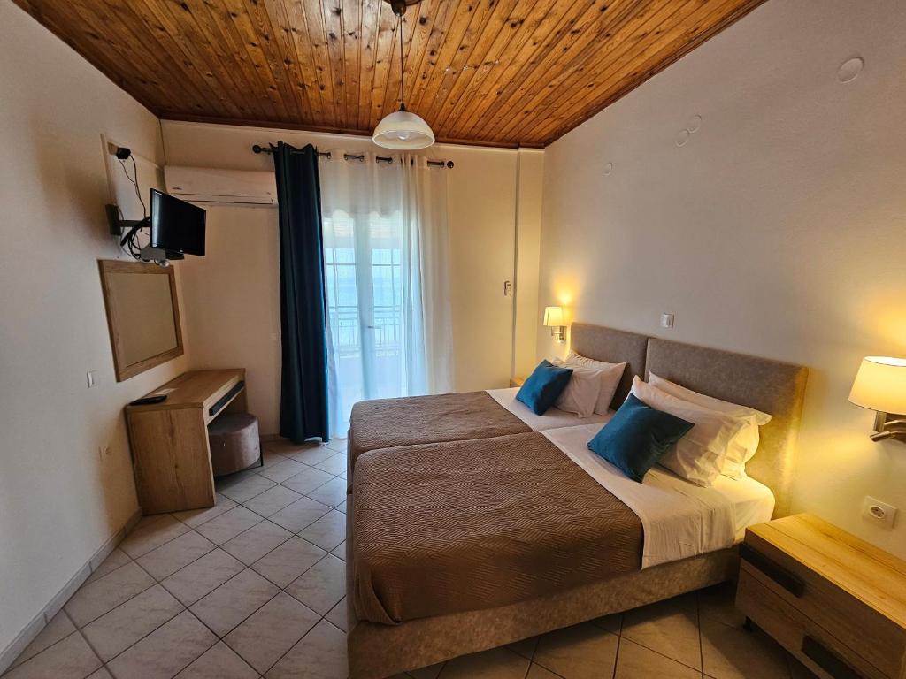 a bedroom with a large bed with a wooden ceiling at Fotini's Apartments - Pelekas Beach in Pelekas