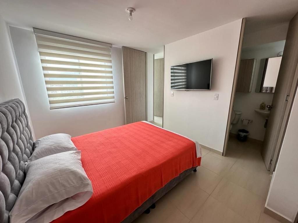 a bedroom with a red bed and a flat screen tv at GURUS FR | Apto. Tranquilo para familias | Naturaleza in Dosquebradas