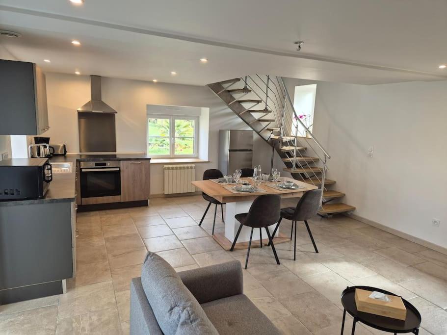 une cuisine et une salle à manger avec une table et un escalier dans l'établissement Gîte Gaïa au cœur de la campagne, à Le Champ-de-la-Pierre