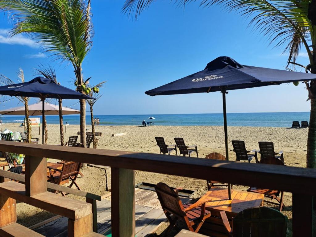 a beach with chairs and umbrellas and the ocean at Zakua Beach in Guachaca