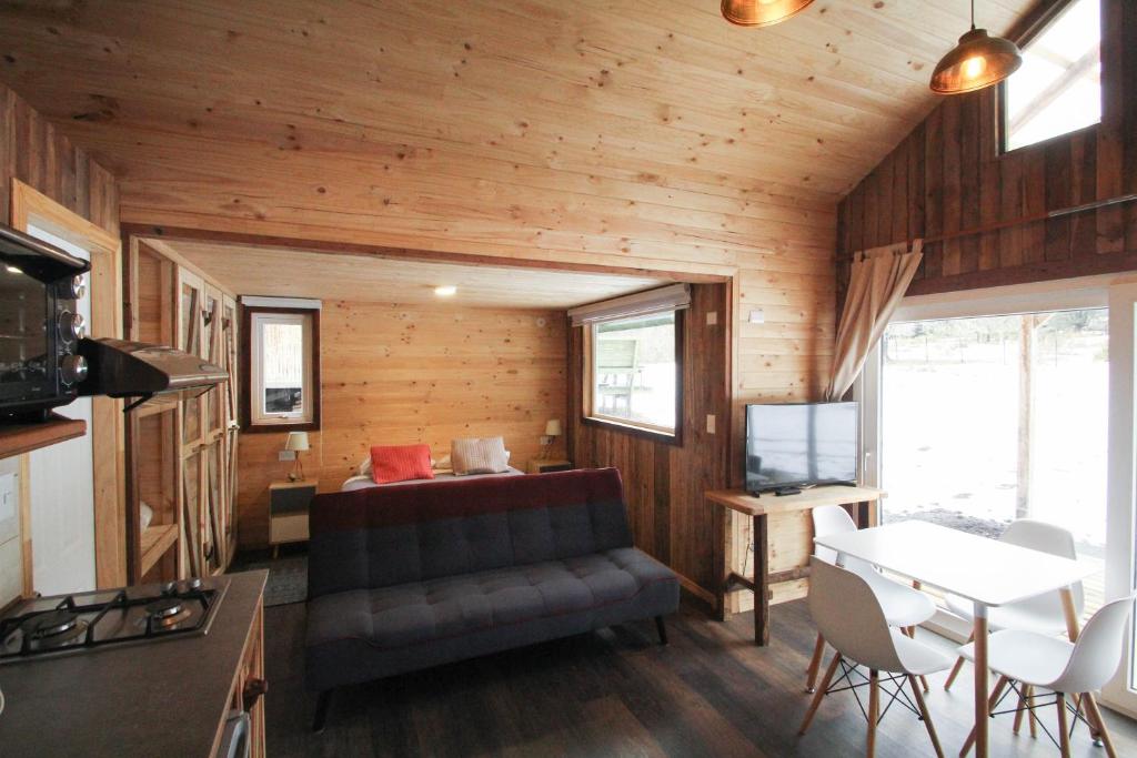 a living room of a tiny house with a couch and a table at Hostal Dos Volcanes in Malalcahuello