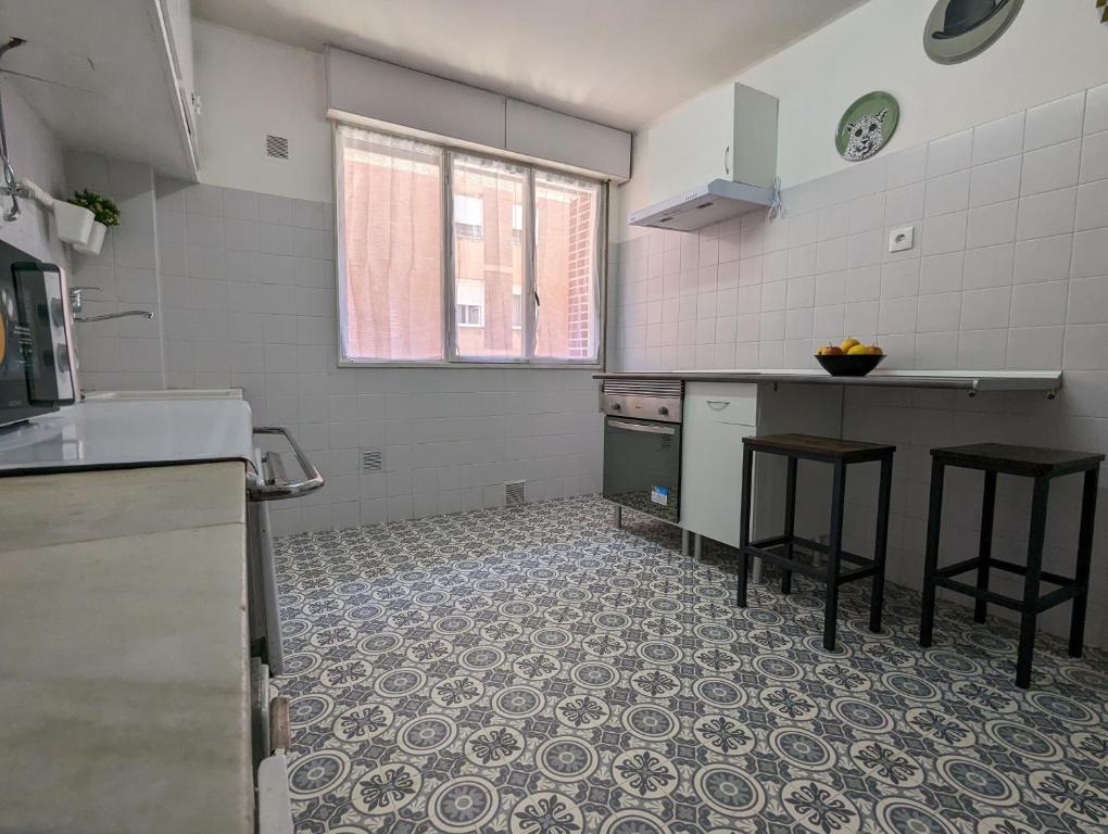 a kitchen with a counter and stools in a room at El rincón del Arbeyal in Gijón