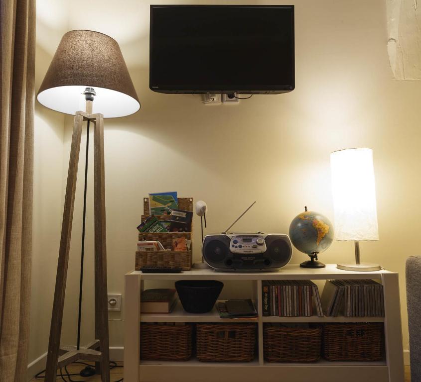 a living room with a tv and a table with a lamp at Le Studio du Gouverneur in Honfleur