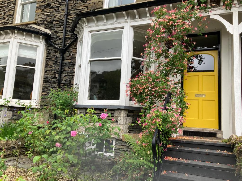 een gele deur op een huis met bloemen bij The Roses in Windermere