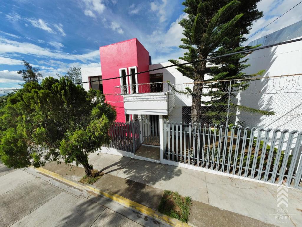een roze en wit huis met een hek bij Casa Embi Oaxaca in Oaxaca City