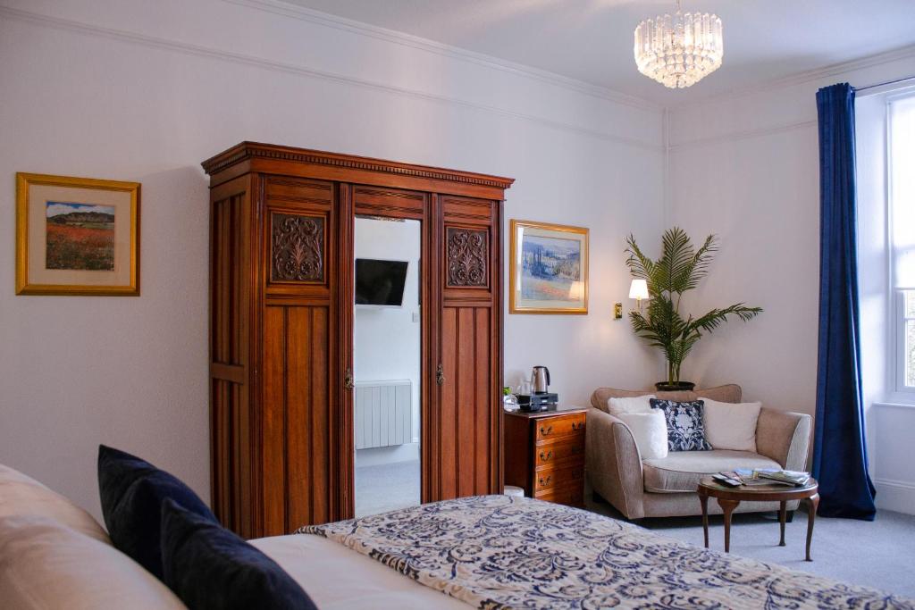 a bedroom with a large wooden cabinet and a chair at Gresham Court in Torquay