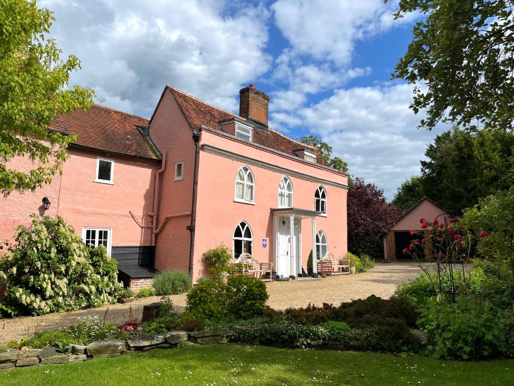 una gran casa rosa con patio en The Cottage Guest House en Bishops Stortford