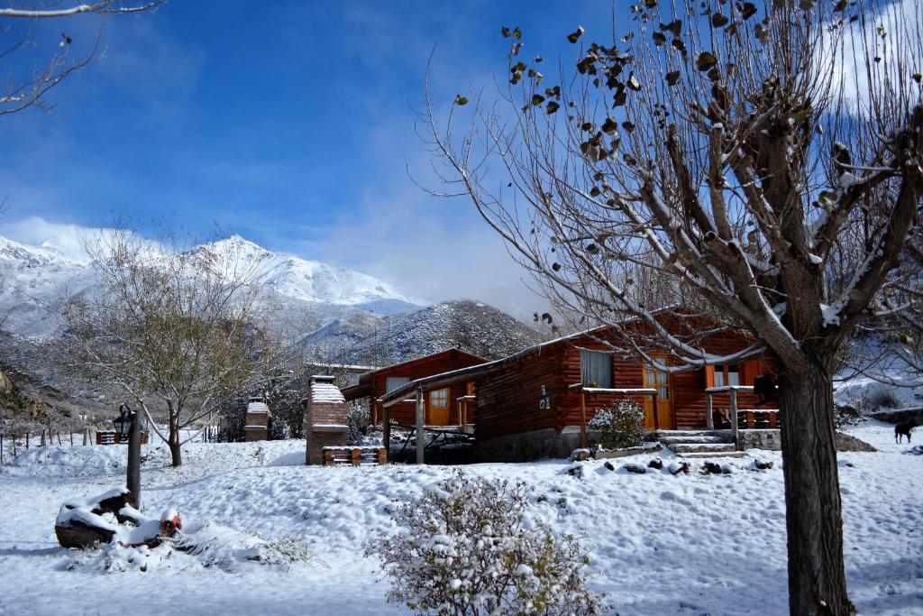 une cabine dans la neige avec des montagnes en arrière-plan dans l'établissement Kpriccio Cabanas, à Potrerillos