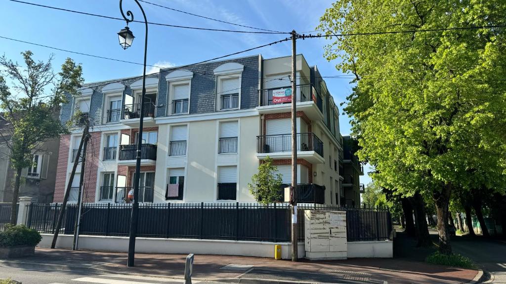 un bâtiment blanc avec une clôture devant dans l'établissement 2 pièces standing entre Disneyland et Paris, à Neuilly-Plaisance
