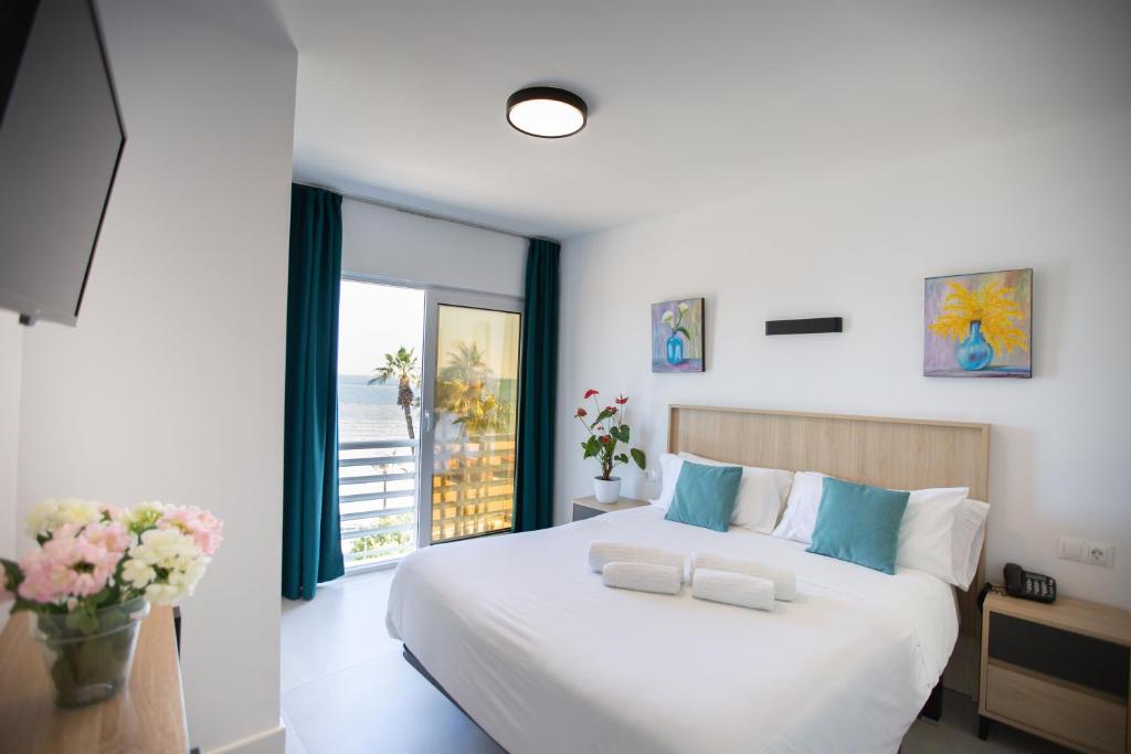 Un dormitorio con una gran cama blanca y una ventana en Hotel Mediterráneo, en Estepona