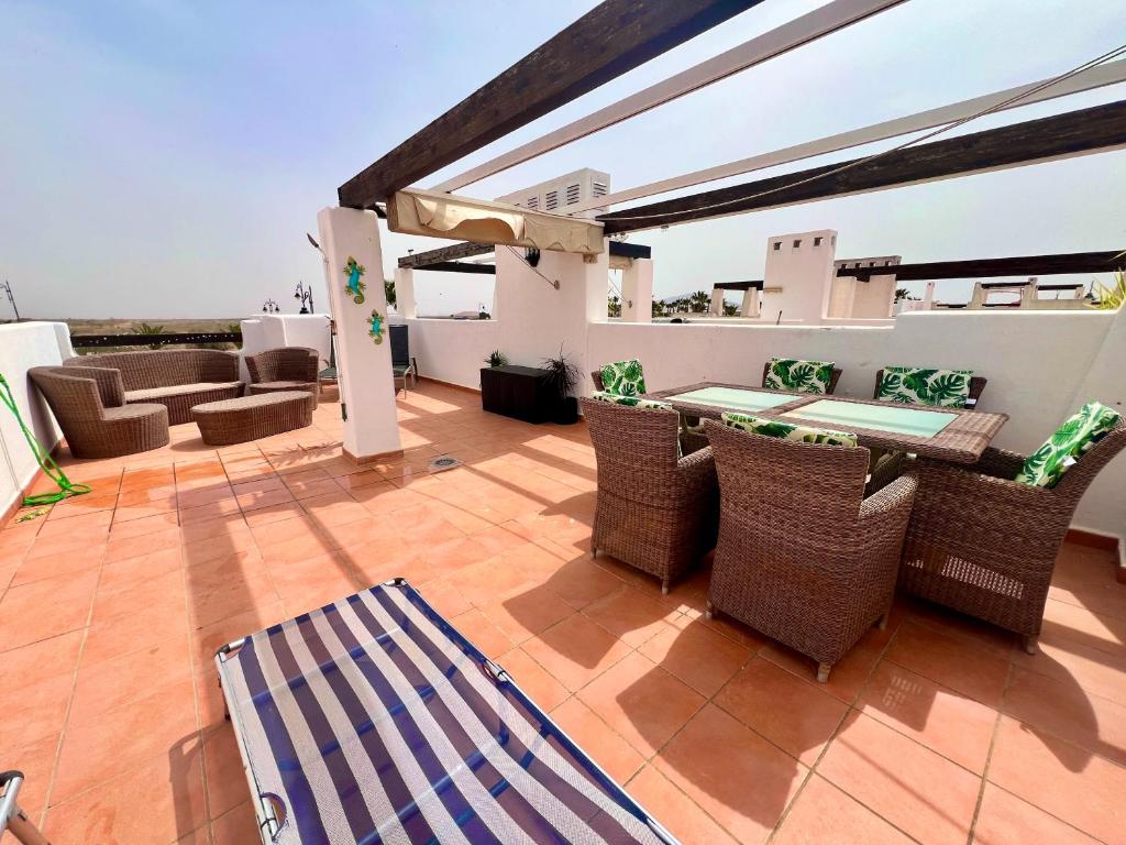 a patio with wicker chairs and tables on a roof at Condado de Alhama JARDIN 13 SV62 in El Romero