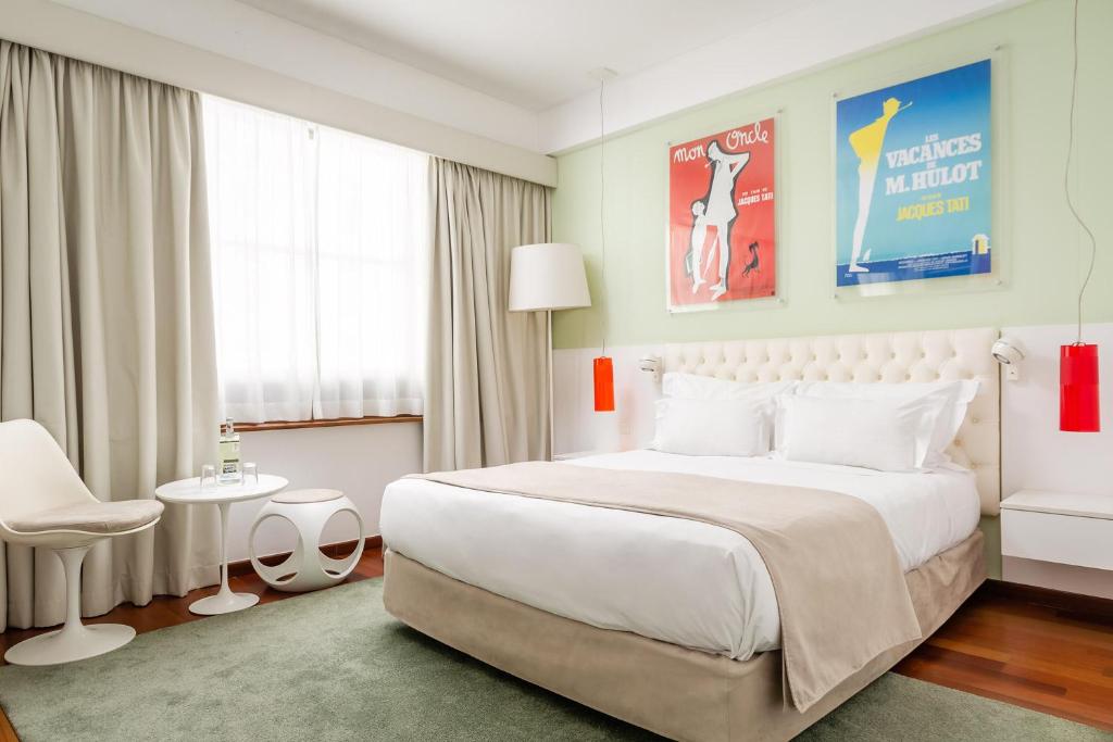 um quarto com uma grande cama branca e uma cadeira em Hotel Florida em Lisboa