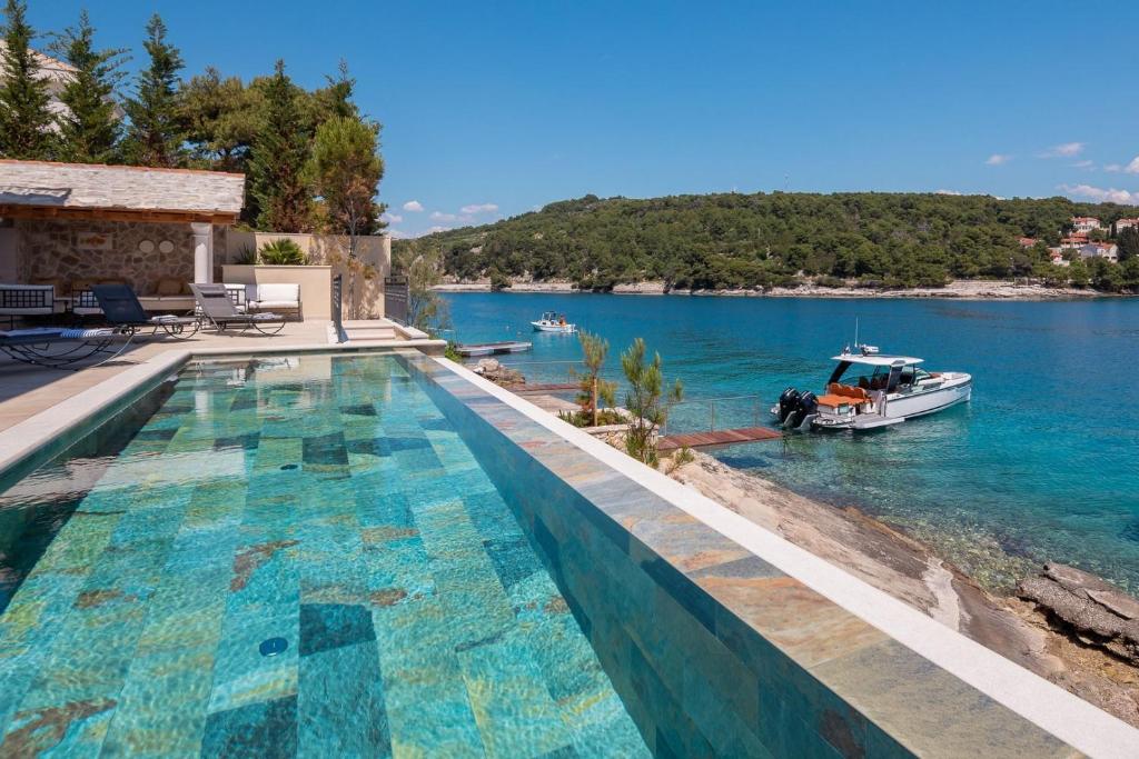 una piscina con un barco en el agua en Luxury Villa Bohemian 1 heated pool near sea, en Selca