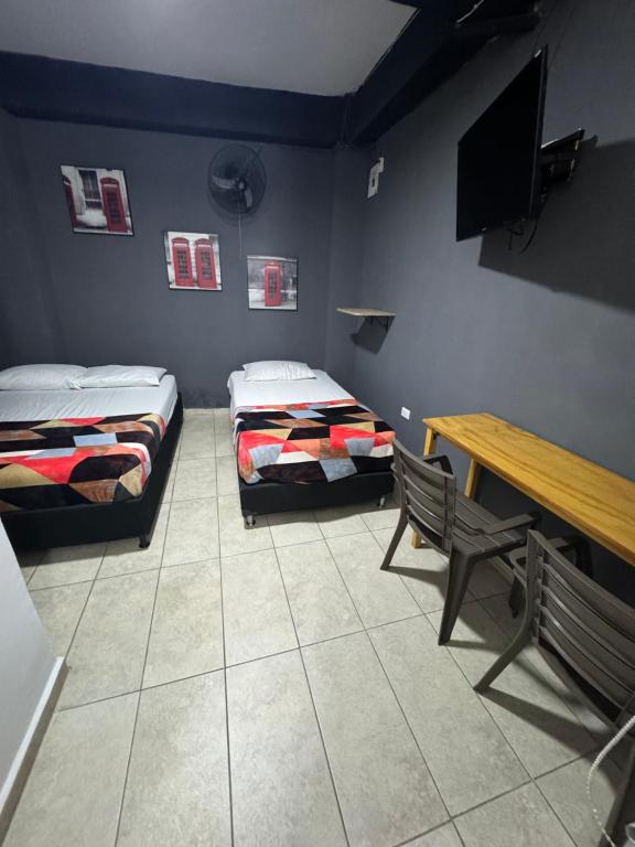 2 camas en una habitación con mesa y banco en HOTEL SELECT, en Medellín