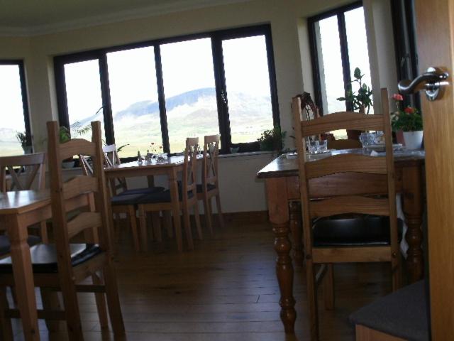 a dining room with tables and chairs and windows at Benview Bed and Breakfast in Staffin
