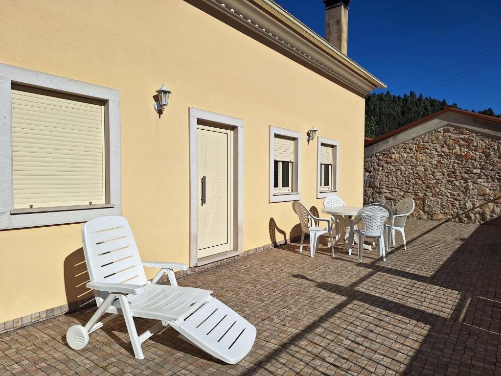 a patio with chairs and a table in front of a house at Casa do Pastana in Ansião