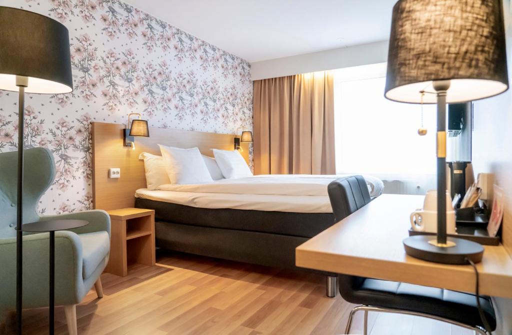 a hotel room with a bed and a desk and chairs at First Hotel Dragonen in Umeå