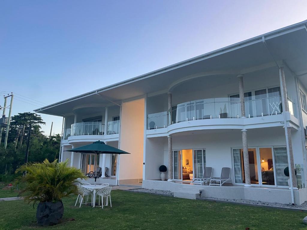 un gran edificio blanco con mesa y sillas en Tropic Villa Annex en Grand'Anse Praslin