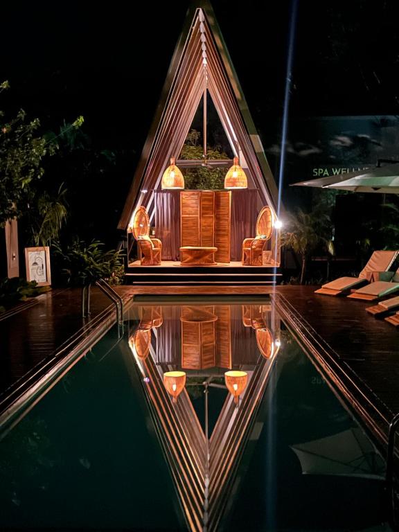 una piccola casa riflette in una piscina di notte di Namu Garden Hotel & Spa a Puerto Viejo