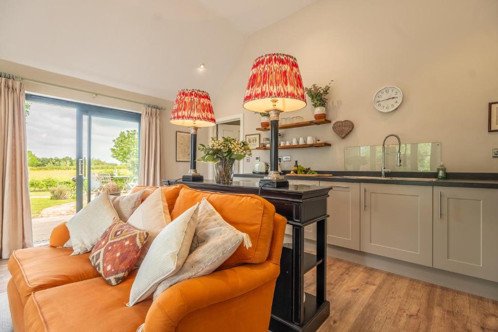 ein Wohnzimmer mit einem orangenen Sofa und einer Küche in der Unterkunft Elegant luxurious cottage - The Dove House in Ipswich