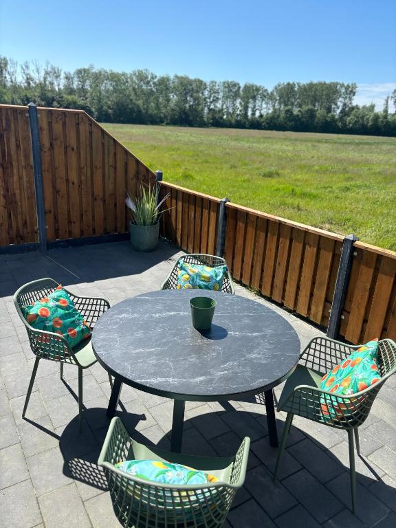a patio with a table and chairs and a fence at De Derrienk 4B met vrij uitzicht! in Biggekerke