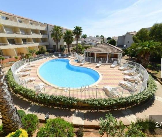 une grande piscine avec des chaises et un bâtiment dans l'établissement Mayflower, au Grau-du-Roi