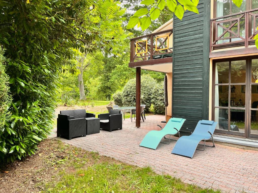 un patio avec des meubles bleus et noirs à côté d'un bâtiment dans l'établissement Villa Bordeaux, à Salles