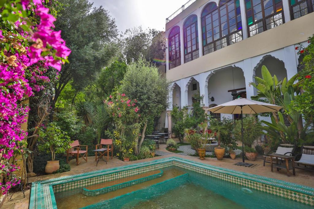 a swimming pool in the courtyard of a house with flowers at Ryad Mabrouka in Fez