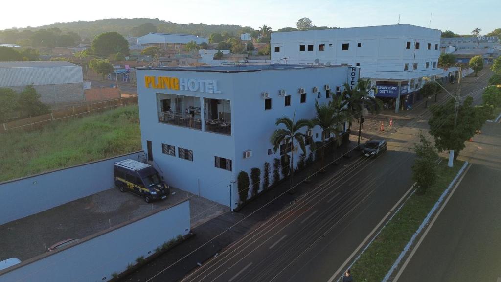 um edifício branco com uma placa amarela ao lado de uma rua em Pling Hotel em Jataí