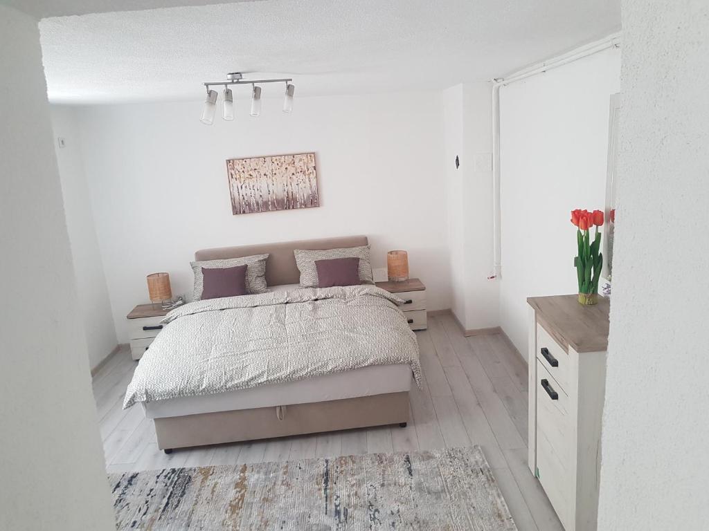 a white bedroom with a bed with purple pillows at Apartman Memo in Sarajevo