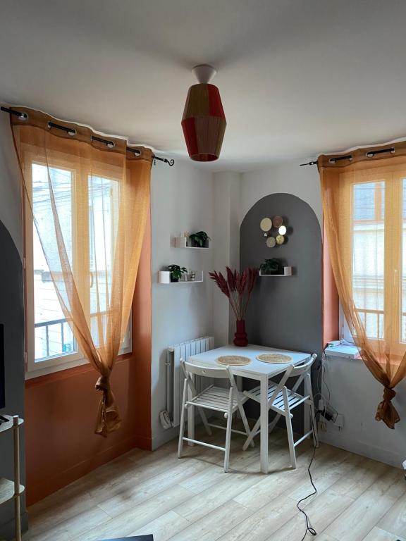 une salle à manger avec une table et deux fenêtres dans l'établissement Petite maison centre ville, à Coulommiers
