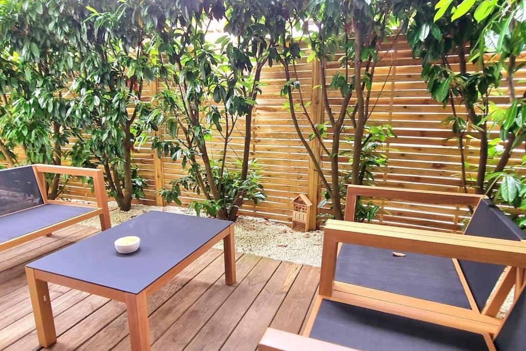 une terrasse en bois avec deux bancs et une table dans l'établissement Bel Appartement au calme avec Rez-de-jardin, à Biscarrosse